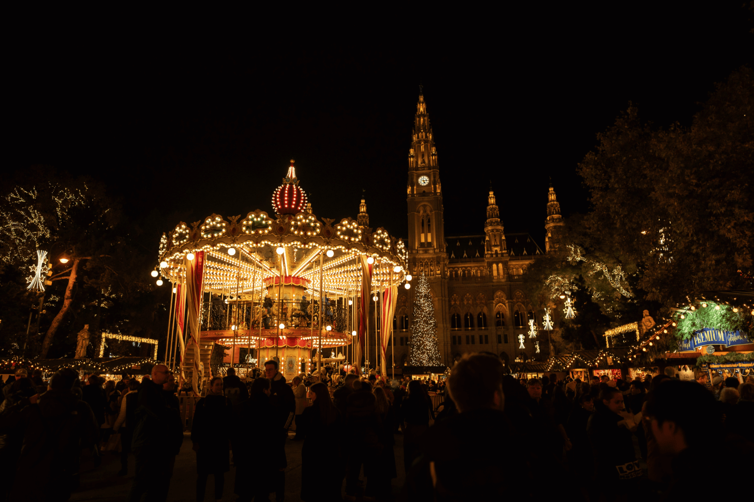 Shooting_Christkindlmarkt_(c)_David_Bohmann_067.jpg Das Foto zeigt den Wiener Christkindlmarkt bei Nacht, festlich beleuchtet. Im Vordergrund ist das Karussell zu sehen, im Hintergrund das Wiener Rathaus.