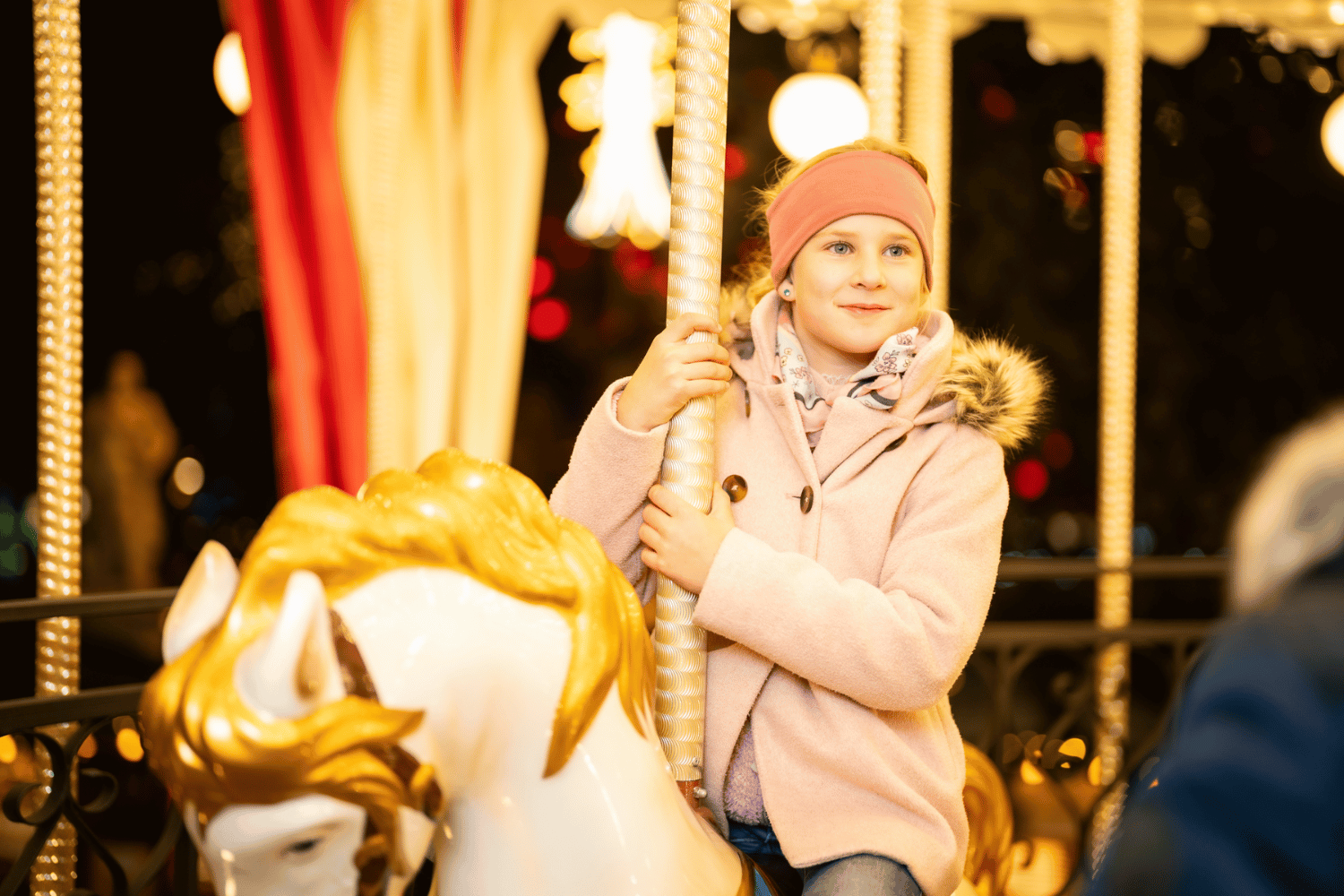 Shooting_Christkindlmarkt_(c)_David_Bohmann_158_komprimiert.jpg Das Foto zeigt ein Mädchen mit rosa Mantel und Haube auf einem Karussellpferd am Wiener Christkindlmarkt.